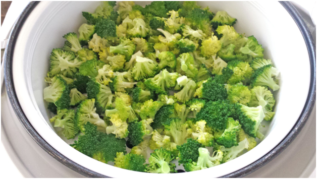 In a rice cooker, how long does it take to steam carrots or broccoli?